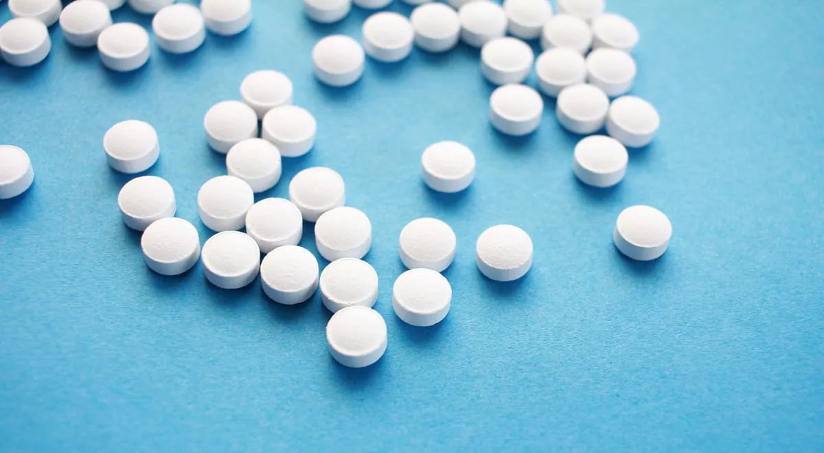 Comprimidos redondos blancos dispersos sobre una superficie azul